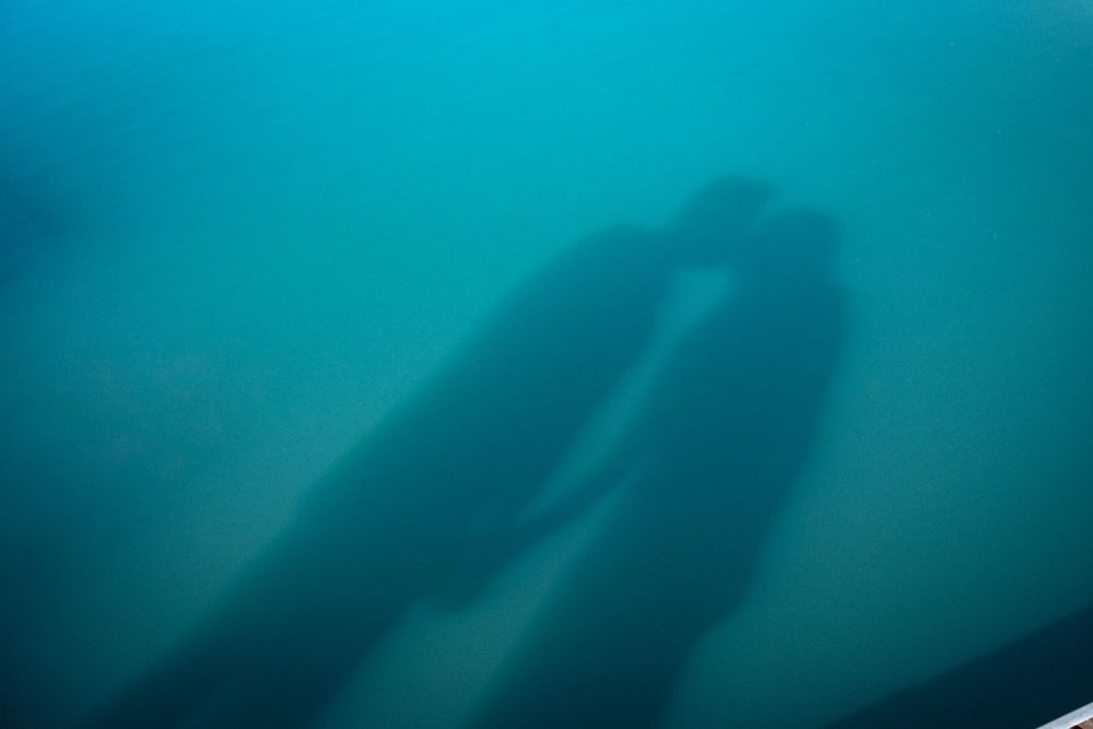 Mysterious underwater shipwreck silhouette submerged in murky teal ocean water, captured in an eerie deep-sea dive photograph.