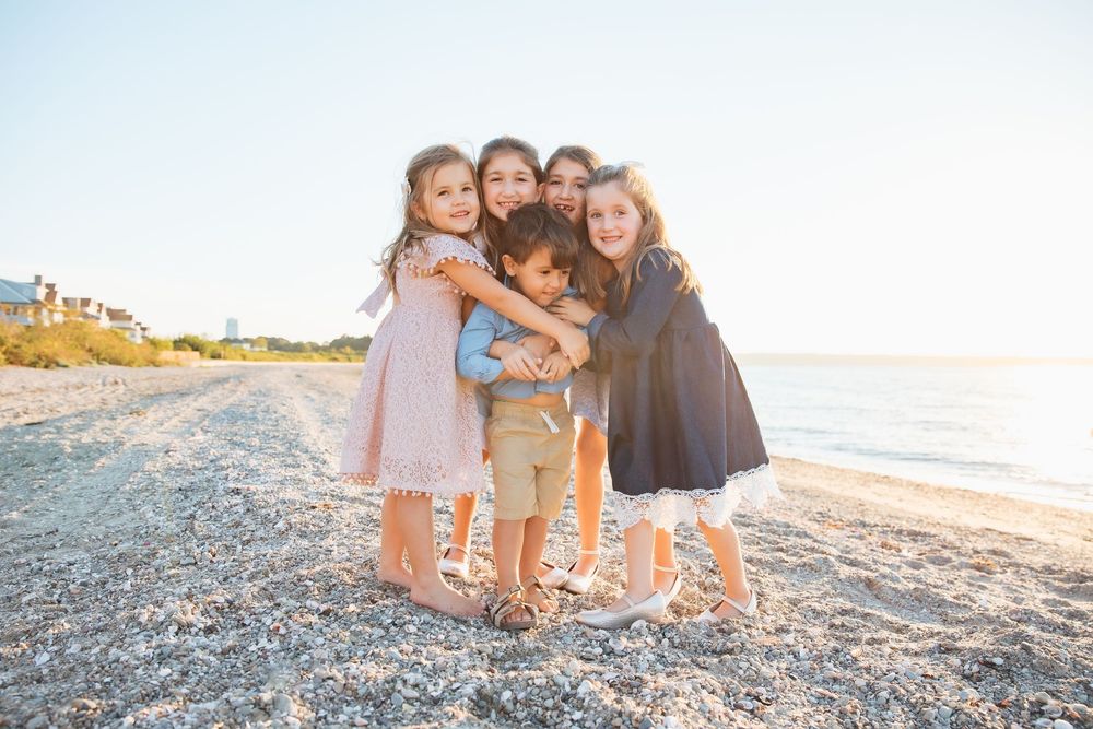 Five children hugging and smiling together on a sunny beach shoreline. extended family photoshoot Portsmouth RI