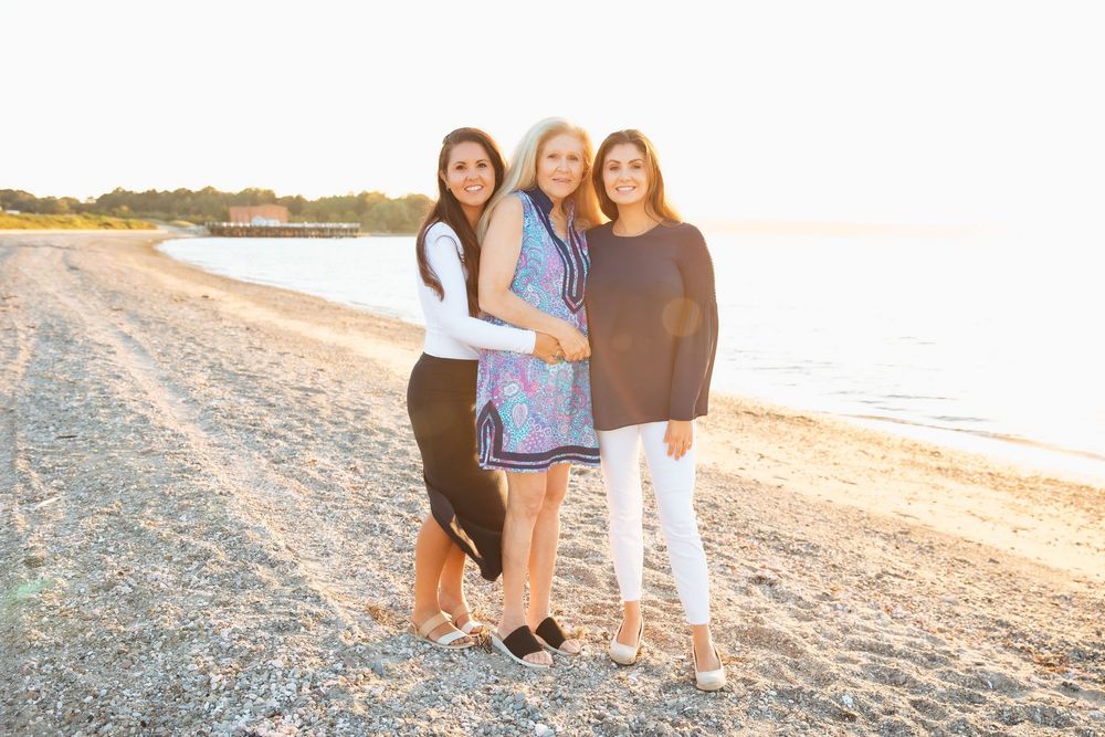 Three women smiling together on a rocky beach at golden hour sunset.  extended family photoshoot Portsmouth RI