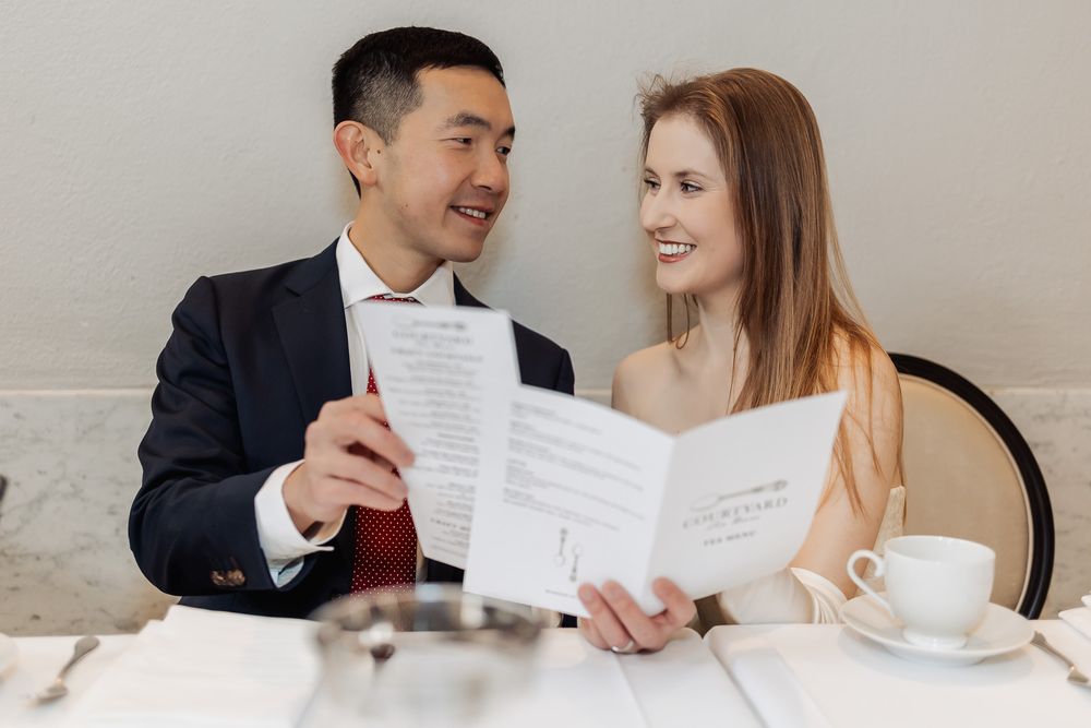 Couple smiling at each other while reviewing menus at an elegant restaurant on a romantic date.