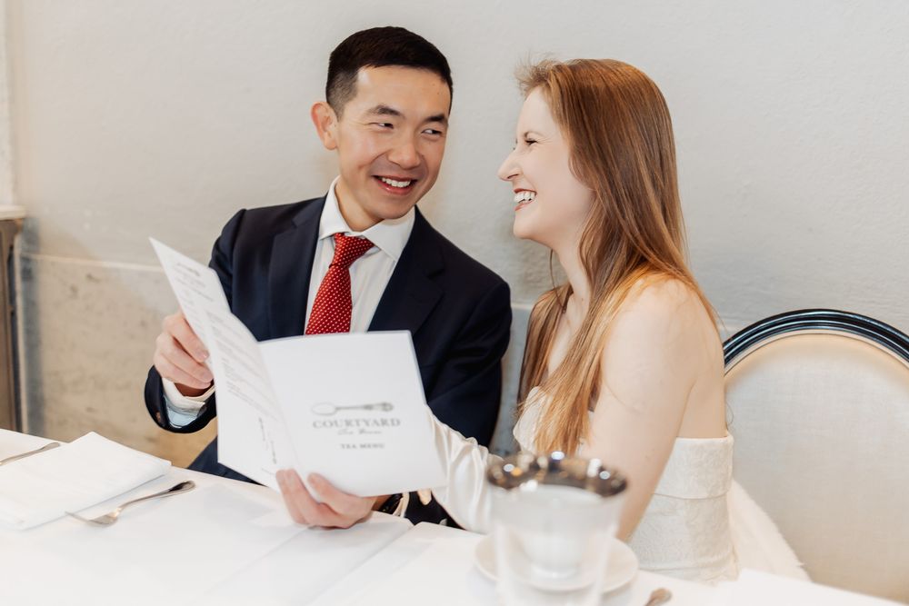 Couple smiling at each other while reviewing a wedding menu at an elegant restaurant table.