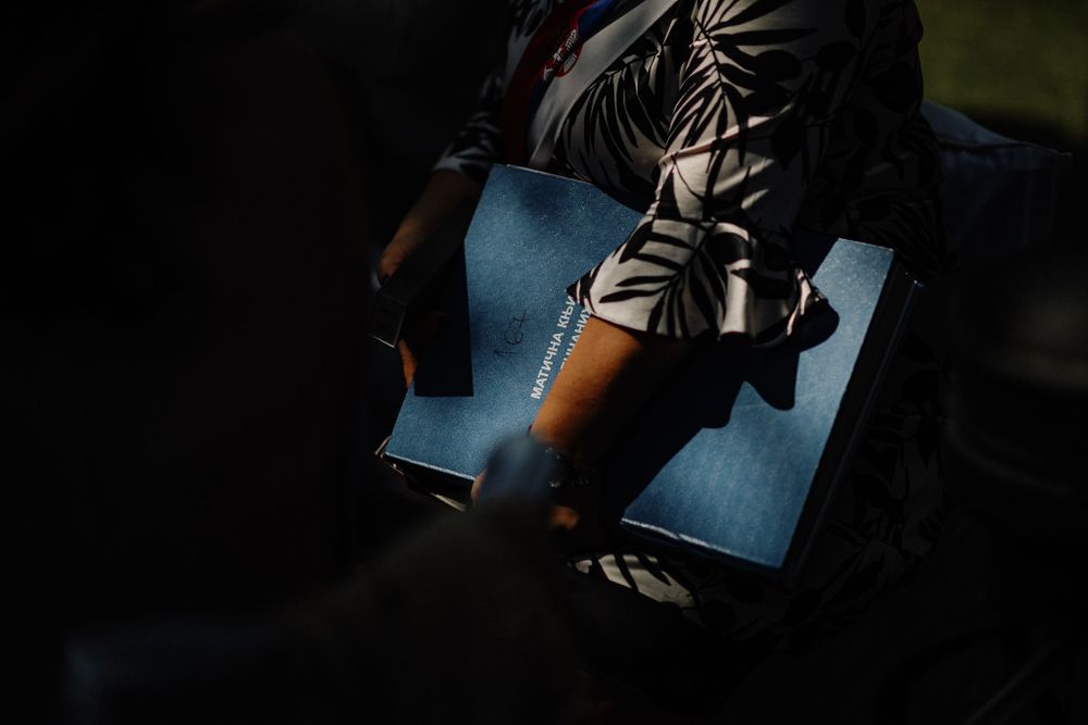 Hands rest on an open blue book in a striped outfit, illuminated by dramatic lighting.