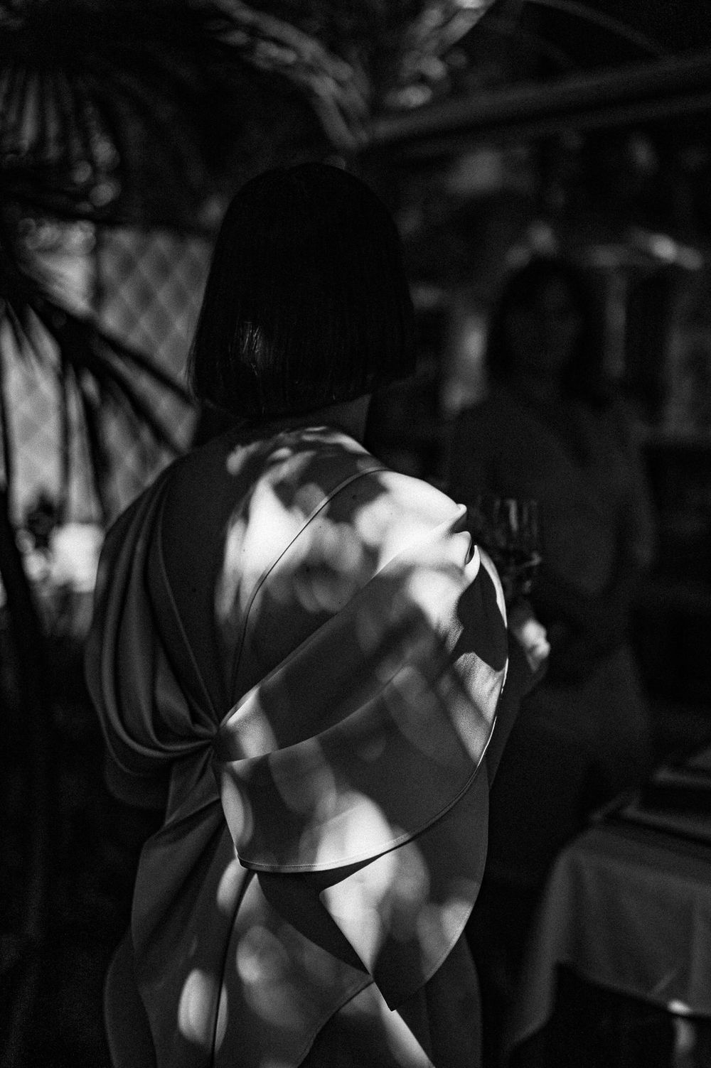 Artistic black and white photo showing dappled light and shadows creating patterns across a figure's silhouette.
