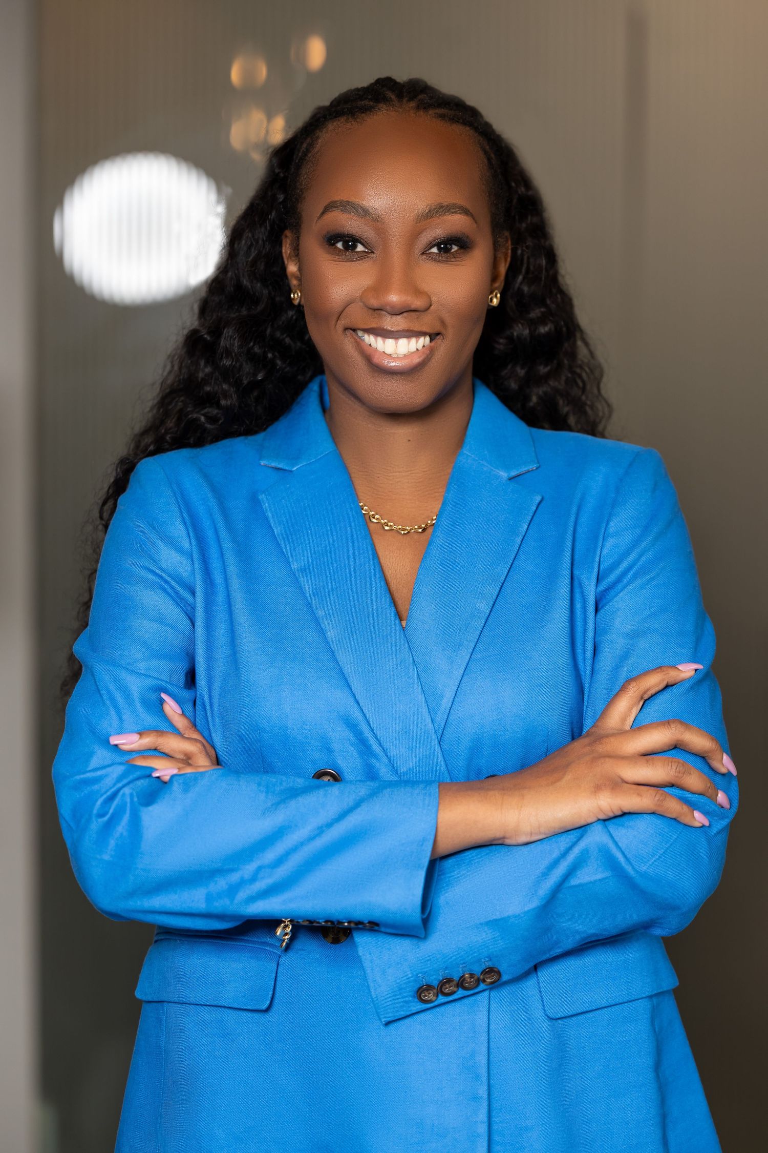Professional portrait featuring bright blue blazer against modern interior with bokeh lighting effects.