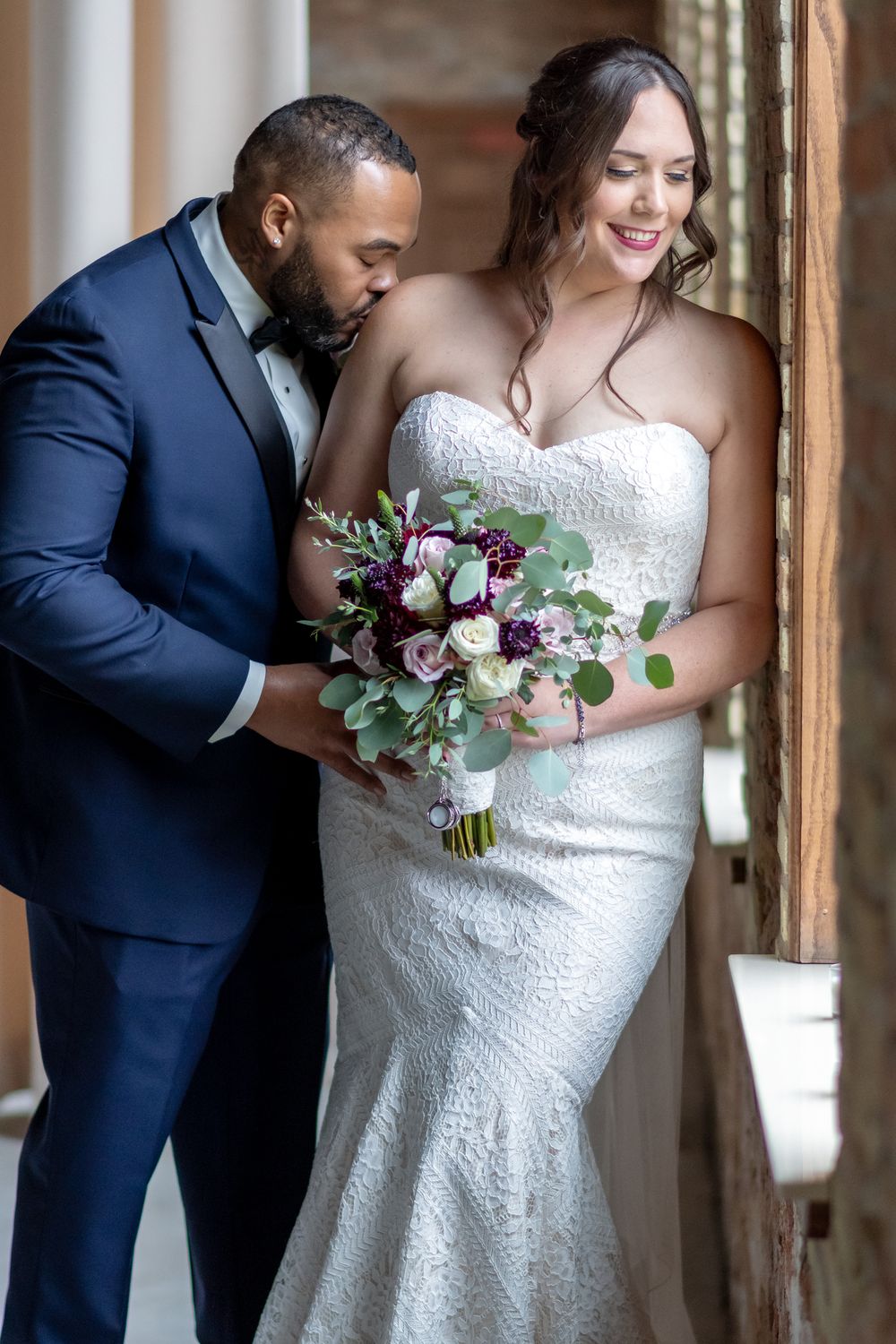 Intimate wedding portrait with bride holding purple and white bouquet.