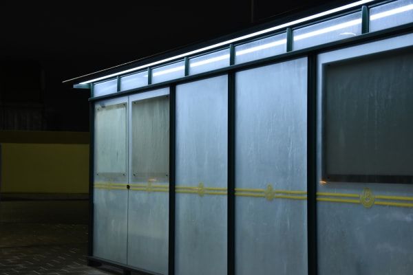 Bus stop in bright lights at night time.