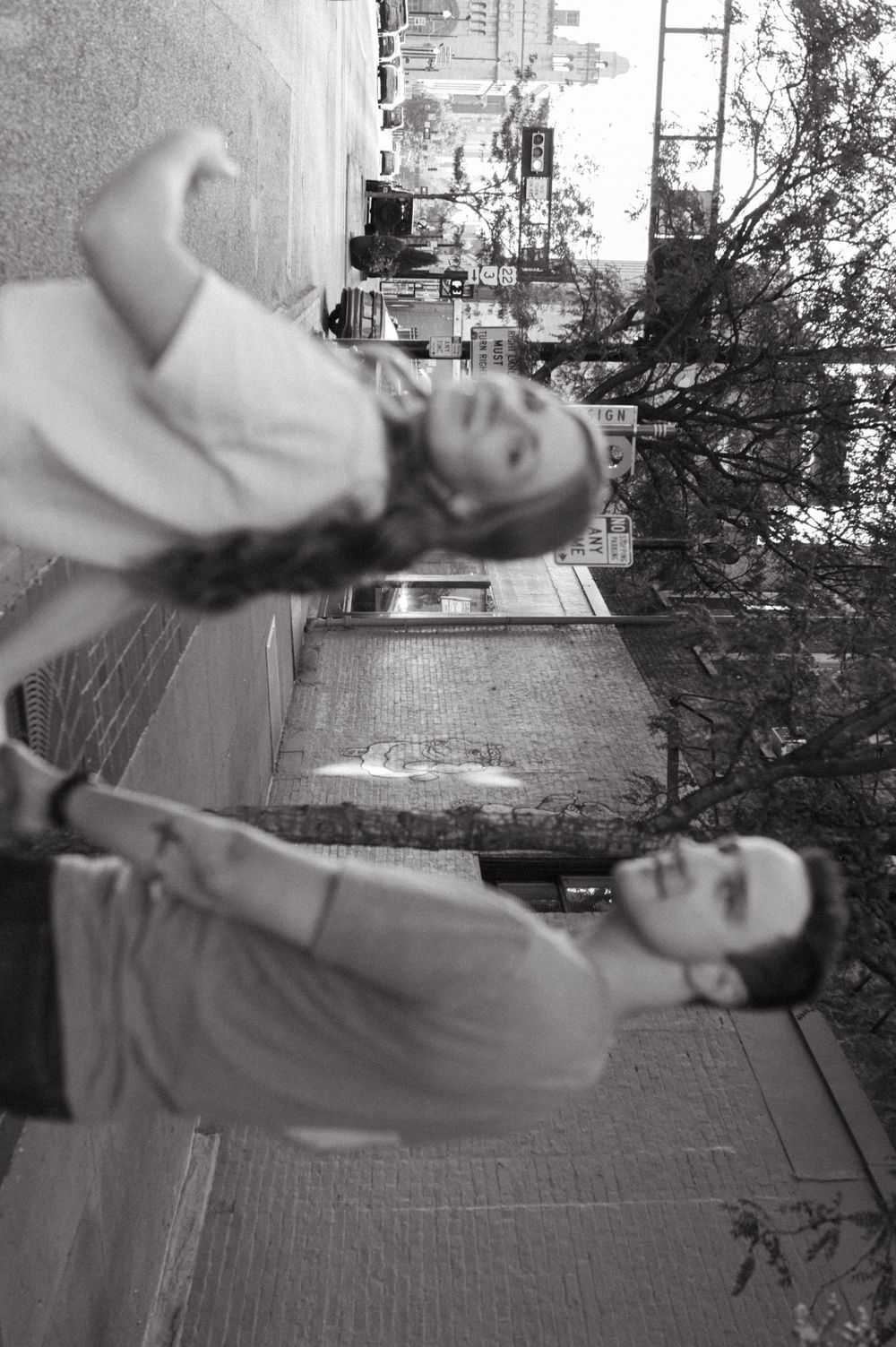 Black and white photo of couple walking together on city street.