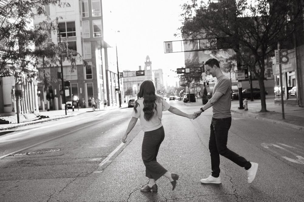 A couple dances playfully together on an urban street in black and white.