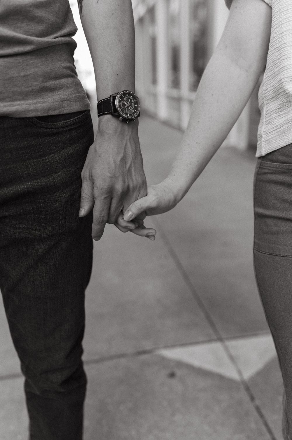 Close-up of two people holding hands with a wristwatch visible.