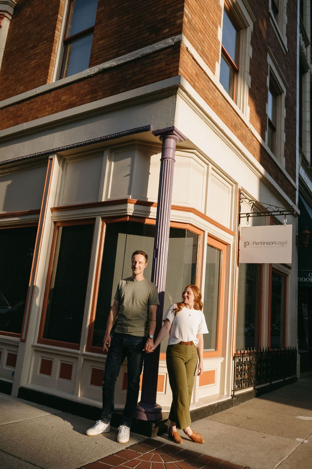 Stylish couple standing outside corner entrance of vintage architectural building.