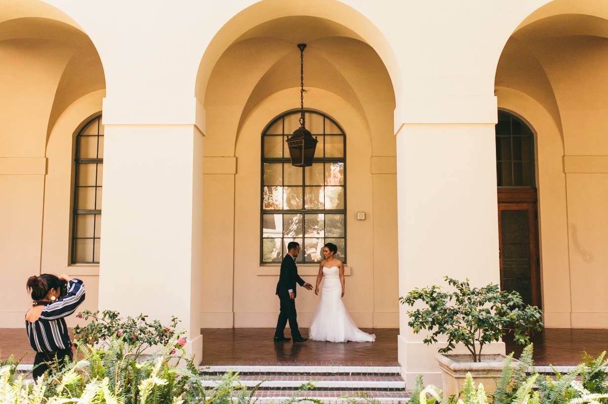 Wedding couple standing under arched corridor with Mediterranean architecture.