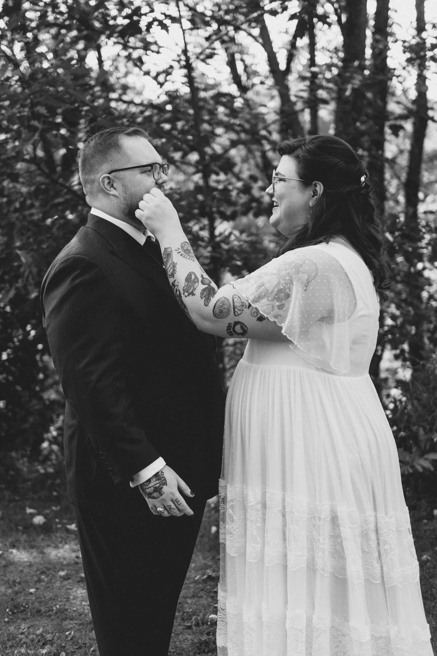 Black and white wedding photo showing an emotional moment during the first look in a wooded outdoor setting.