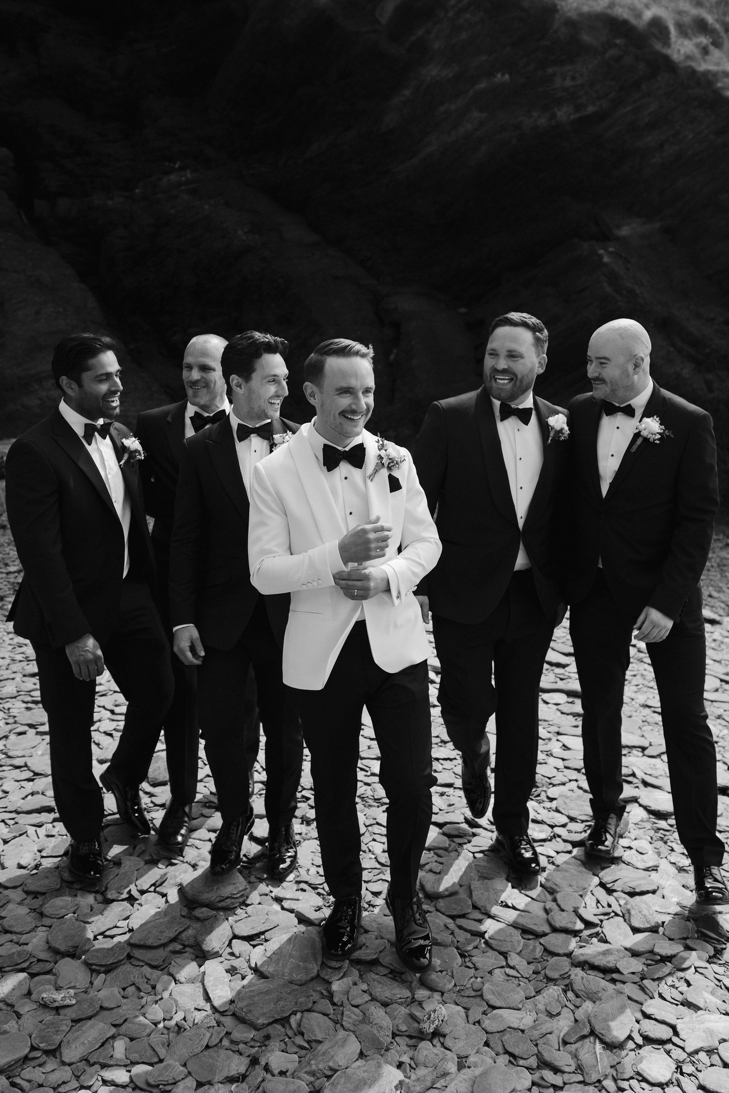 Groom and Groomsmen walking on beach at Tunnels Beach wedding venue in north devon