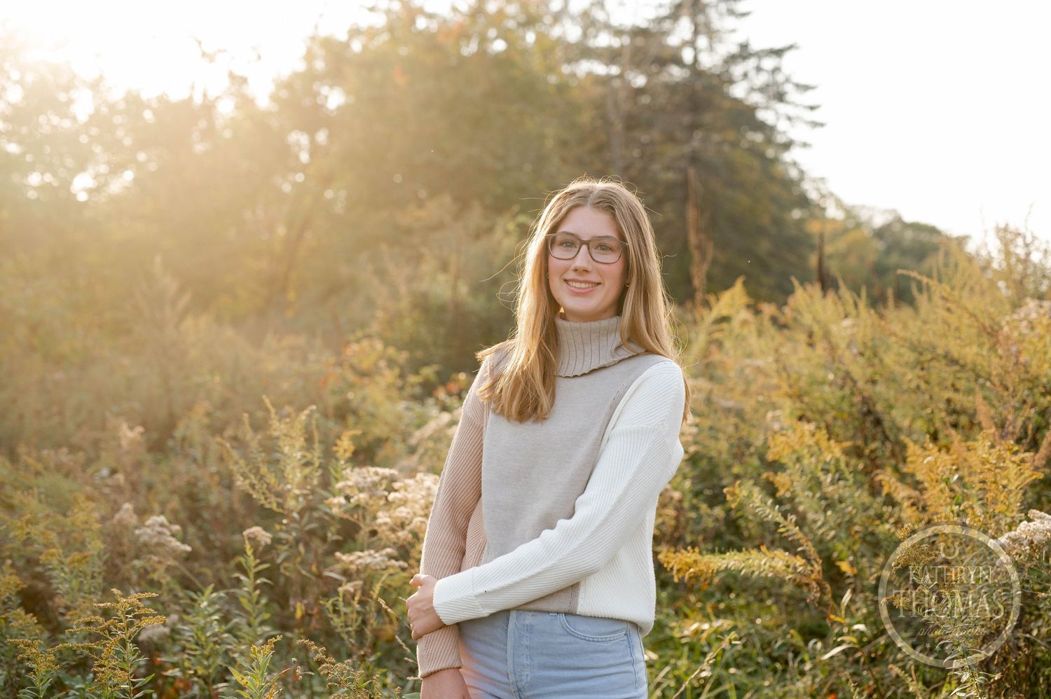 A casual outdoor portrait captured in warm evening light among wild autumn foliage.