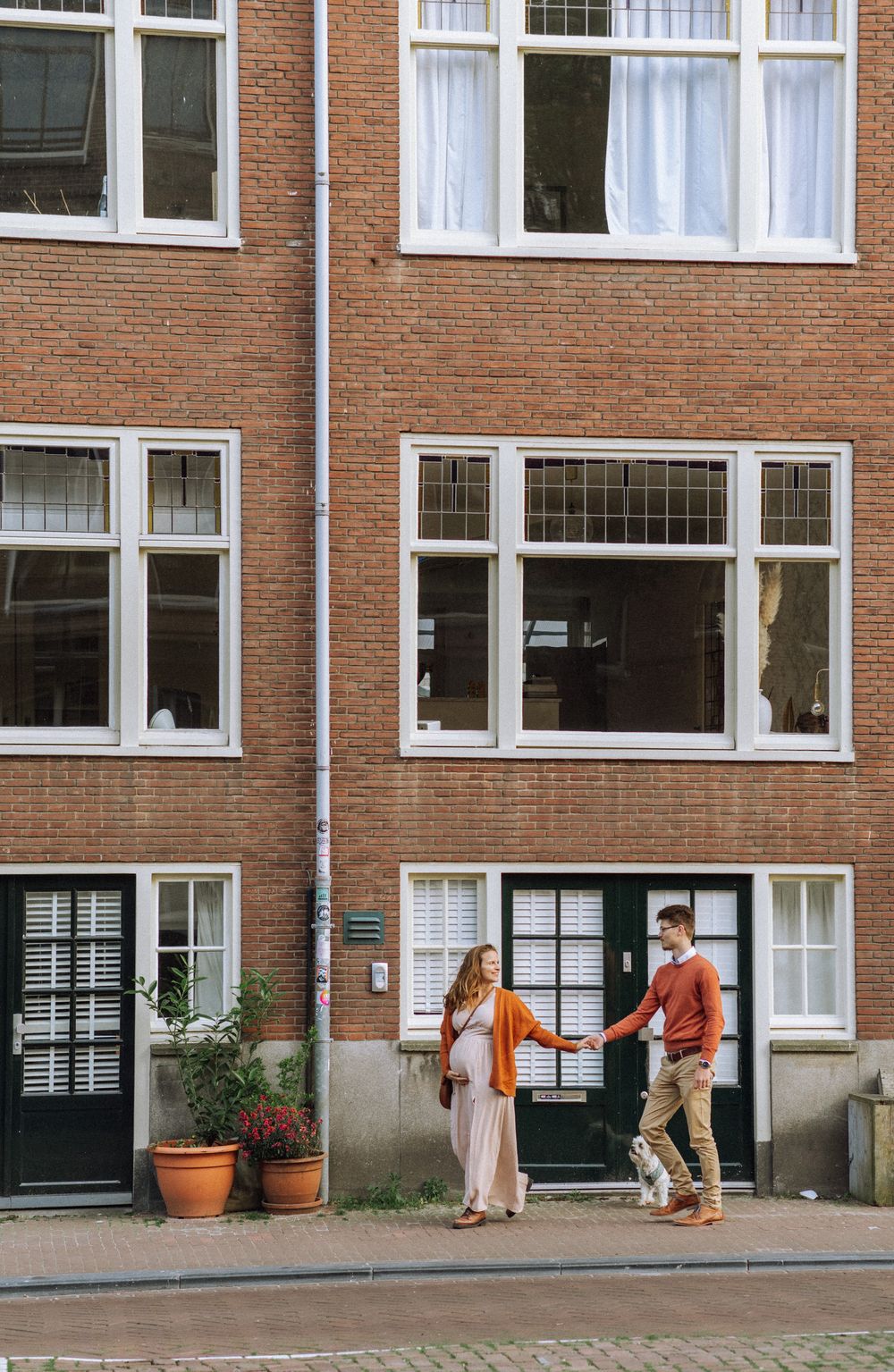 People walking past brick apartment buildings with traditional Dutch architecture.