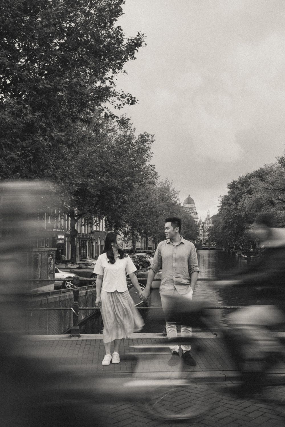 Couple sitting on a bench with blurred motion of passing cyclists in Amsterdam.