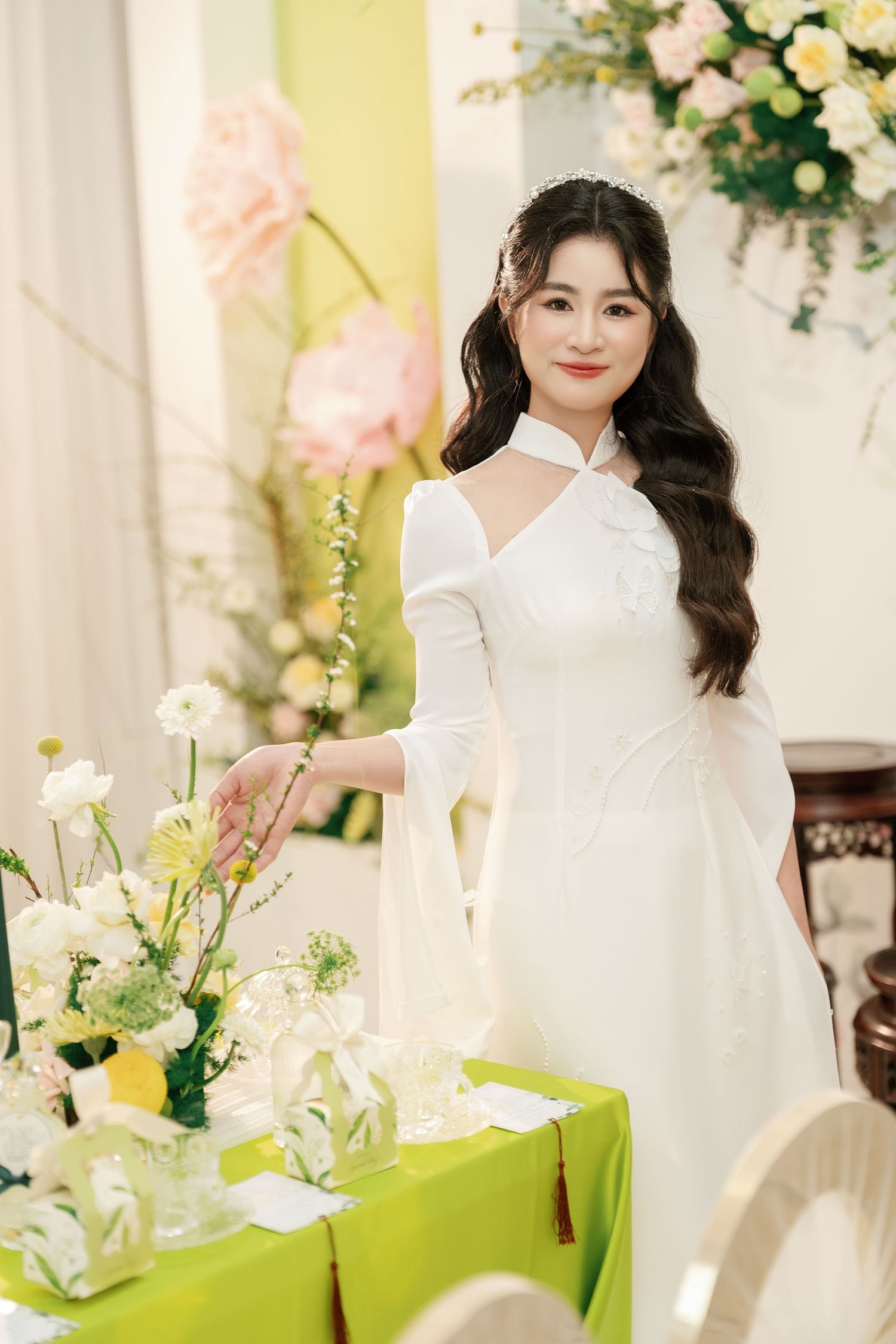 Modern white halter dress with elegant long sleeves photographed against floral and green decor.