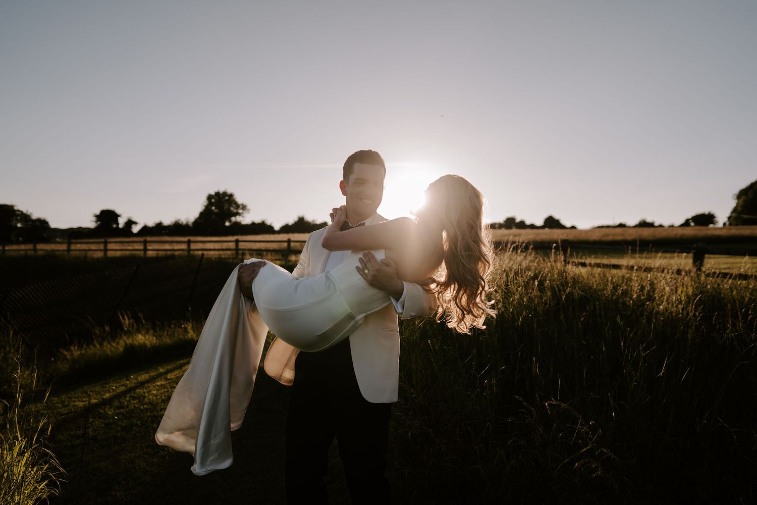 groom lifting and spinning bride during sunset at hamswell house wedding in bath