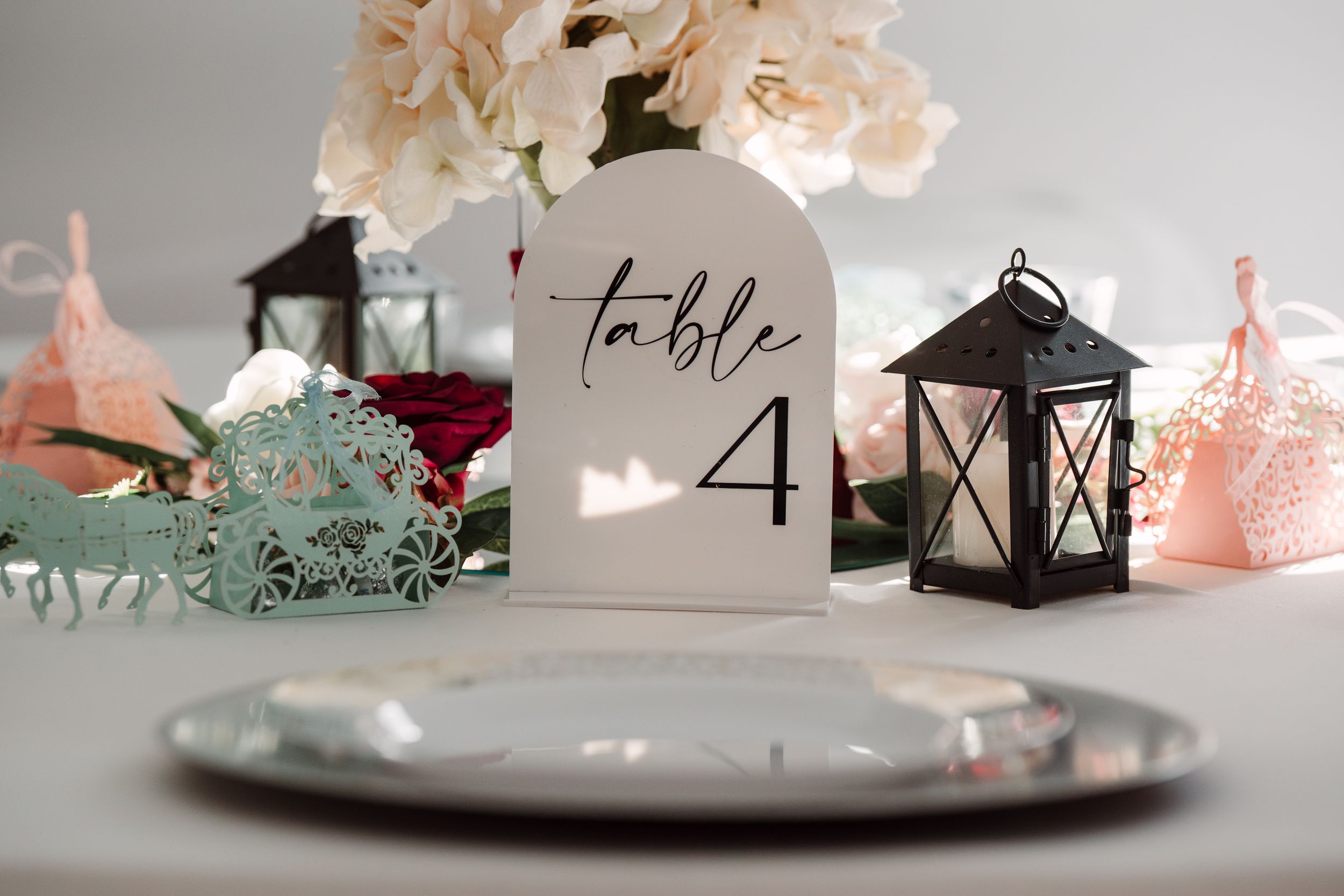 Wedding reception table decor with lantern centerpiece, flowers and table number 4.