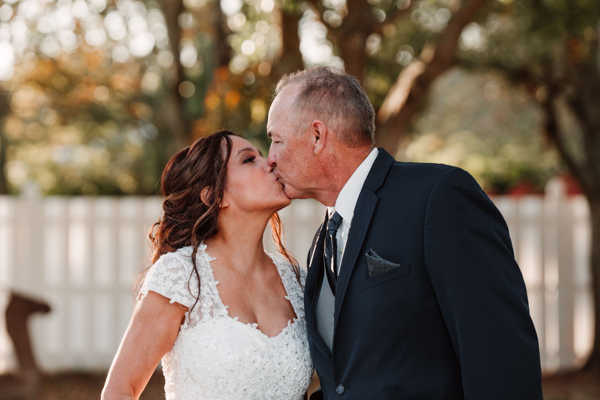 An intimate outdoor wedding moment between two people in formal attire.
