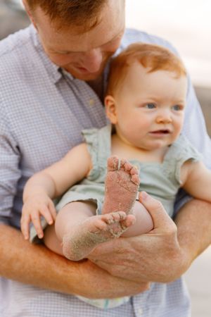 A sandy baby foot close-up while being held at the beach.