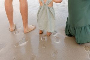 Bare feet leave wet footprints on concrete floor while people in dresses walk through shallow water.