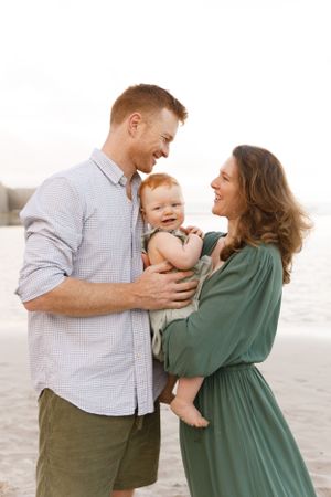 A happy young family enjoying a tender moment together on the beach during golden hour.