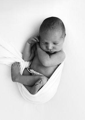 High-key black and white artistic newborn photography series showing baby details against white background.