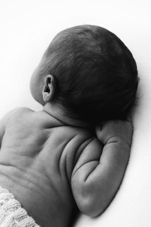 Four black and white photos showing a sleeping baby in different positions against a white background.