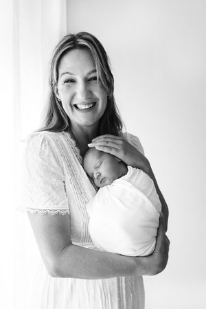 A series of black and white maternity portraits showing a woman in a white dress embracing her baby bump.