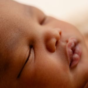 Close-up portrait of peaceful sleeping infant with soft ambient lighting.