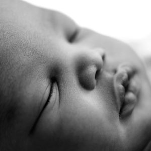 Close-up black and white portrait of a sleeping infant's serene face.