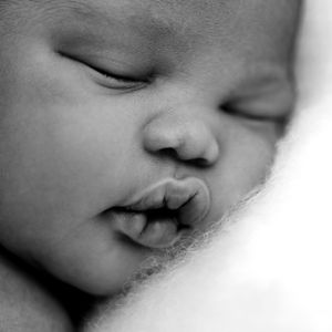 Black and white close-up photograph of a peaceful sleeping baby in soft focus.
