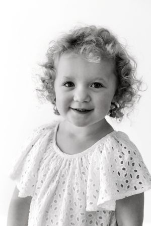 A series of black and white portraits featuring a young child in a delicate white lace dress.
