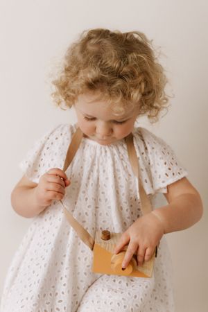 A child in a white eyelet lace dress plays with toys shown in a series of candid moments.