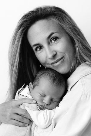 Black and white portrait of parent holding sleeping newborn baby against shoulder in tender embrace.