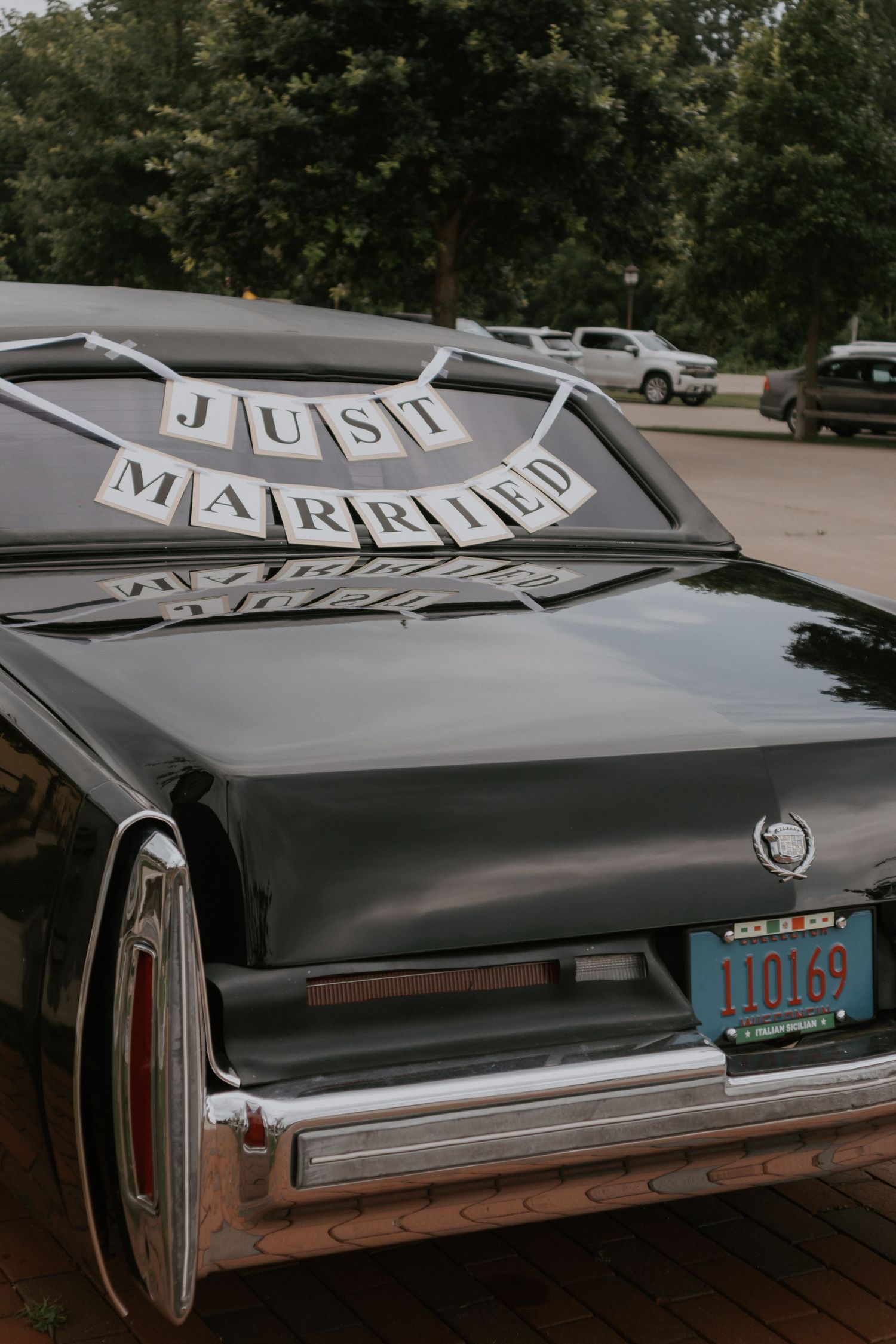 Just Married banner displayed on back window of luxury classic black Cadillac car. Nostalgic aesthetic.