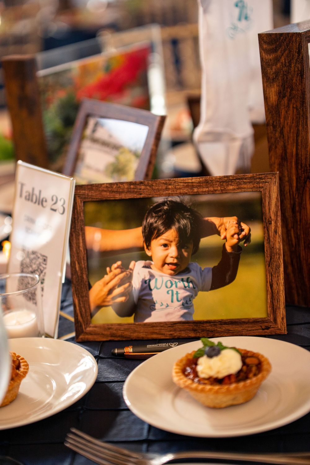Framed photo displayed on a table with dessert plates at a formal event.