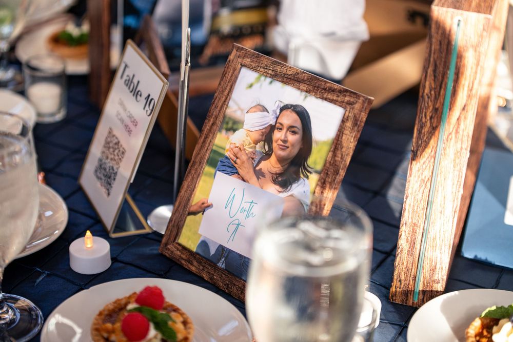 Framed photograph displayed on an elegant dinner table setting with glassware and plates.
