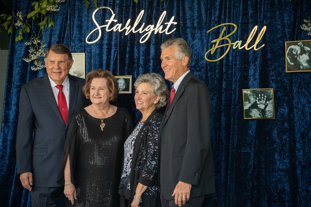 Group photo against blue velvet backdrop at Starlight Ball formal event.