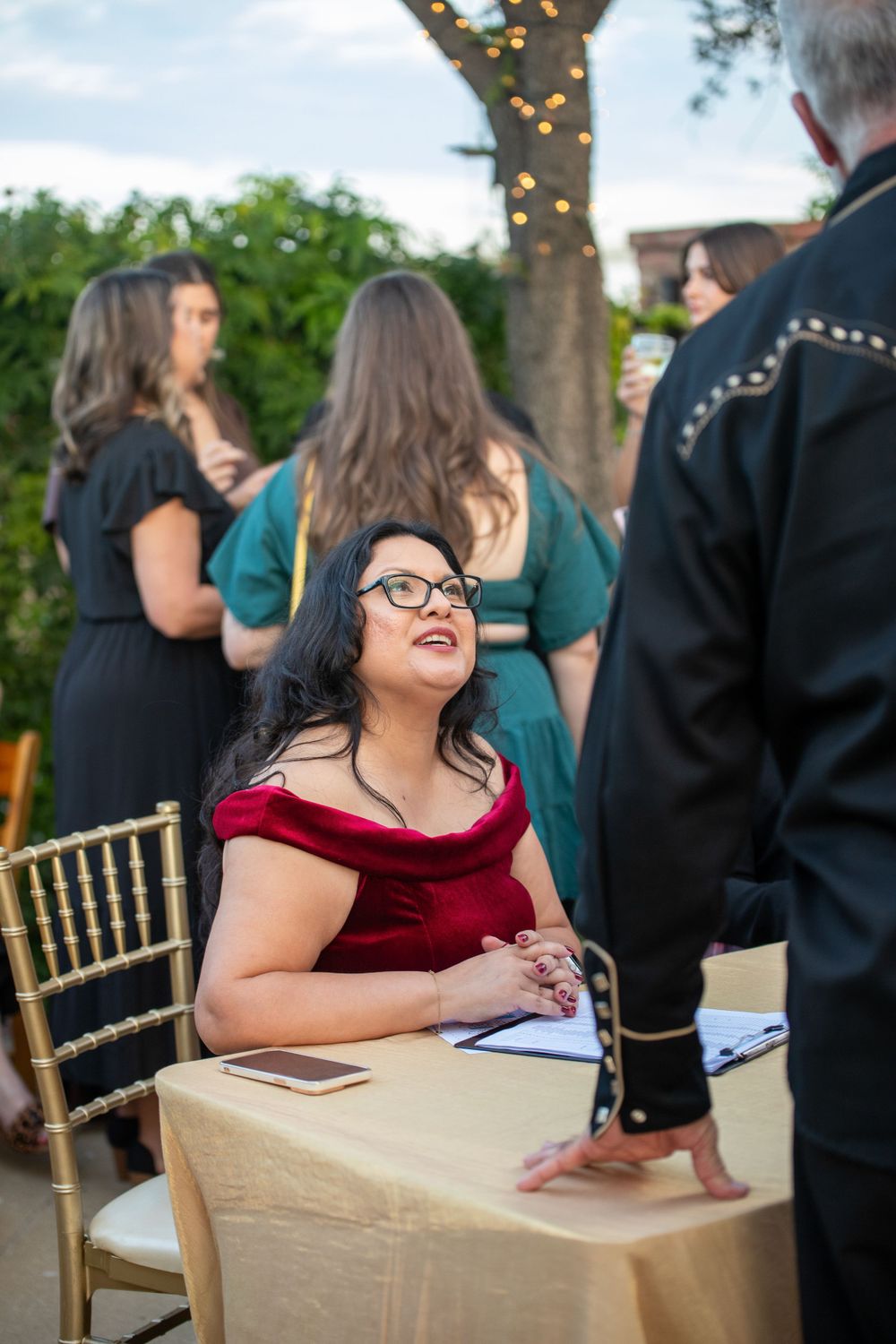 Guest in a red velvet dress seated at a decorated table during an outdoor event.