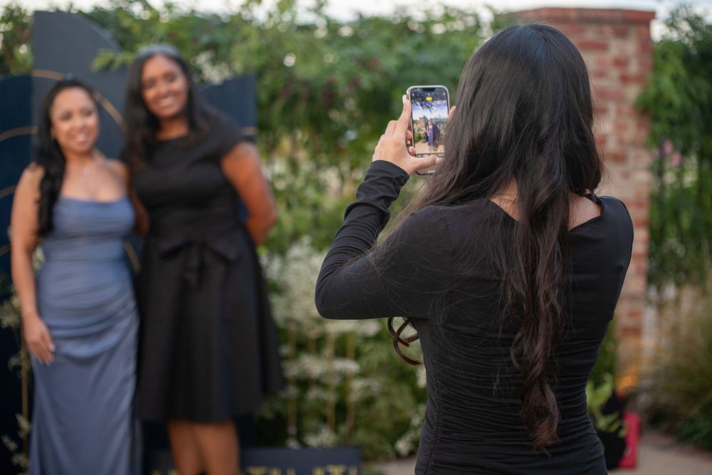 Wedding guests mingling outdoors at a reception with bridesmaids in blue dresses.