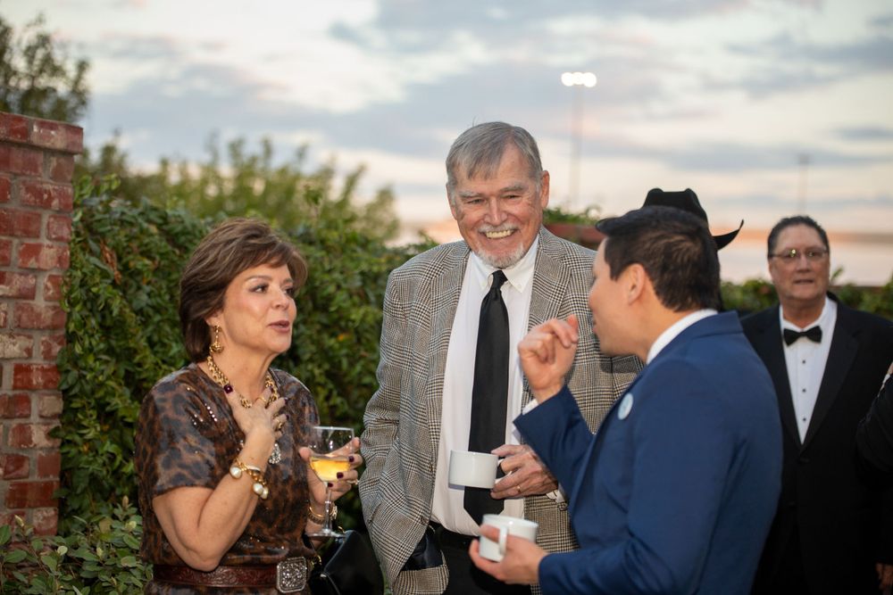 Evening outdoor reception gathering with guests enjoying drinks and conversation.