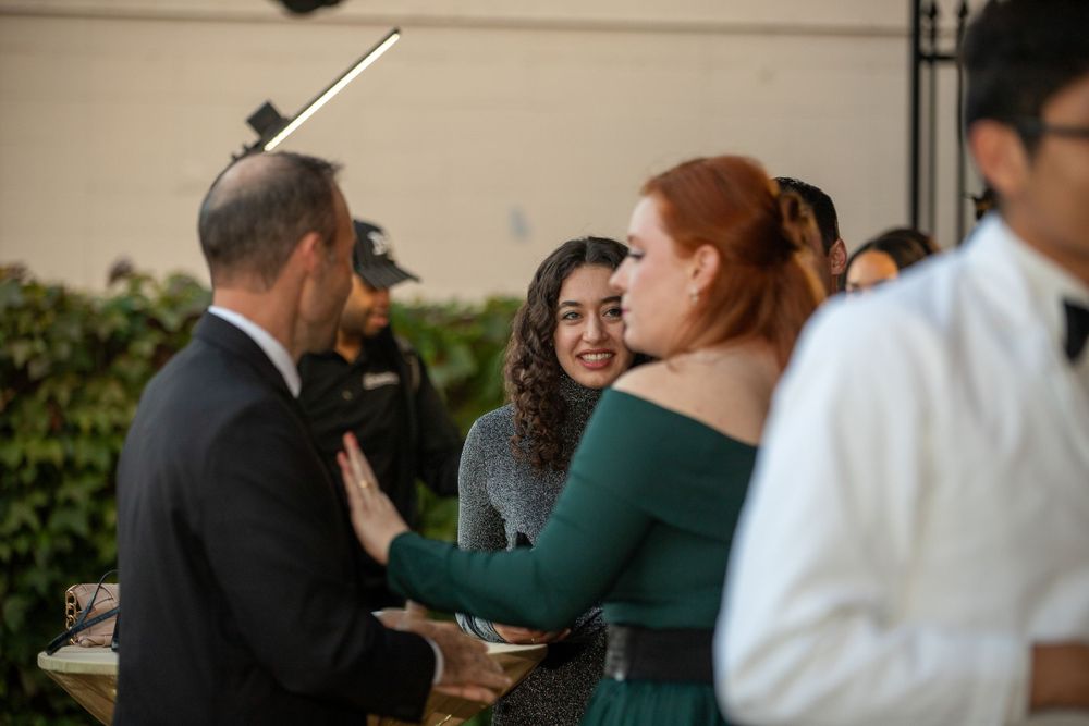 Guests socializing at an outdoor reception with string lights overhead.