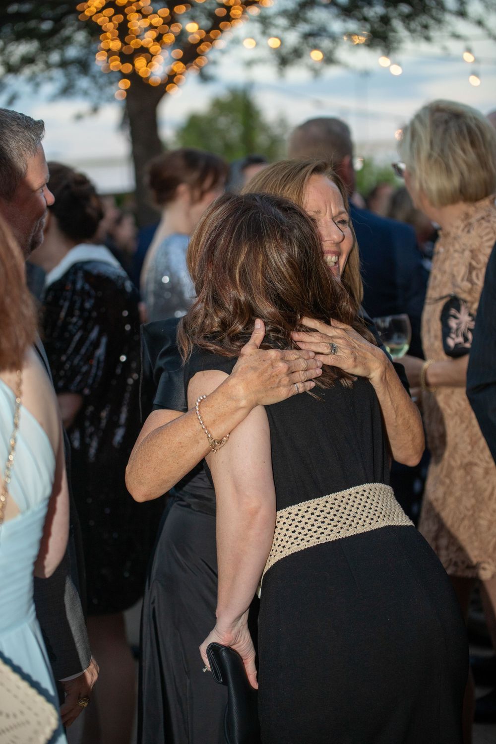Guests dancing and celebrating at an outdoor evening reception under string lights.