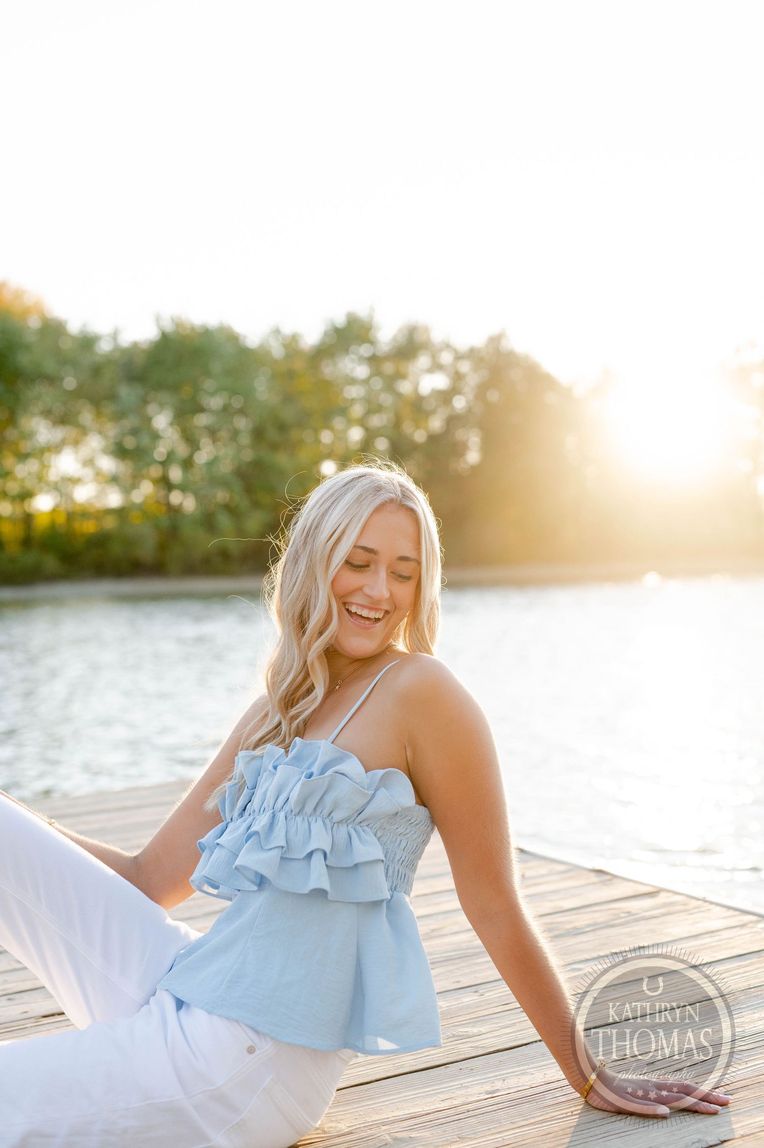 Candid summer portrait showing someone laughing while relaxing on a lakeside dock.