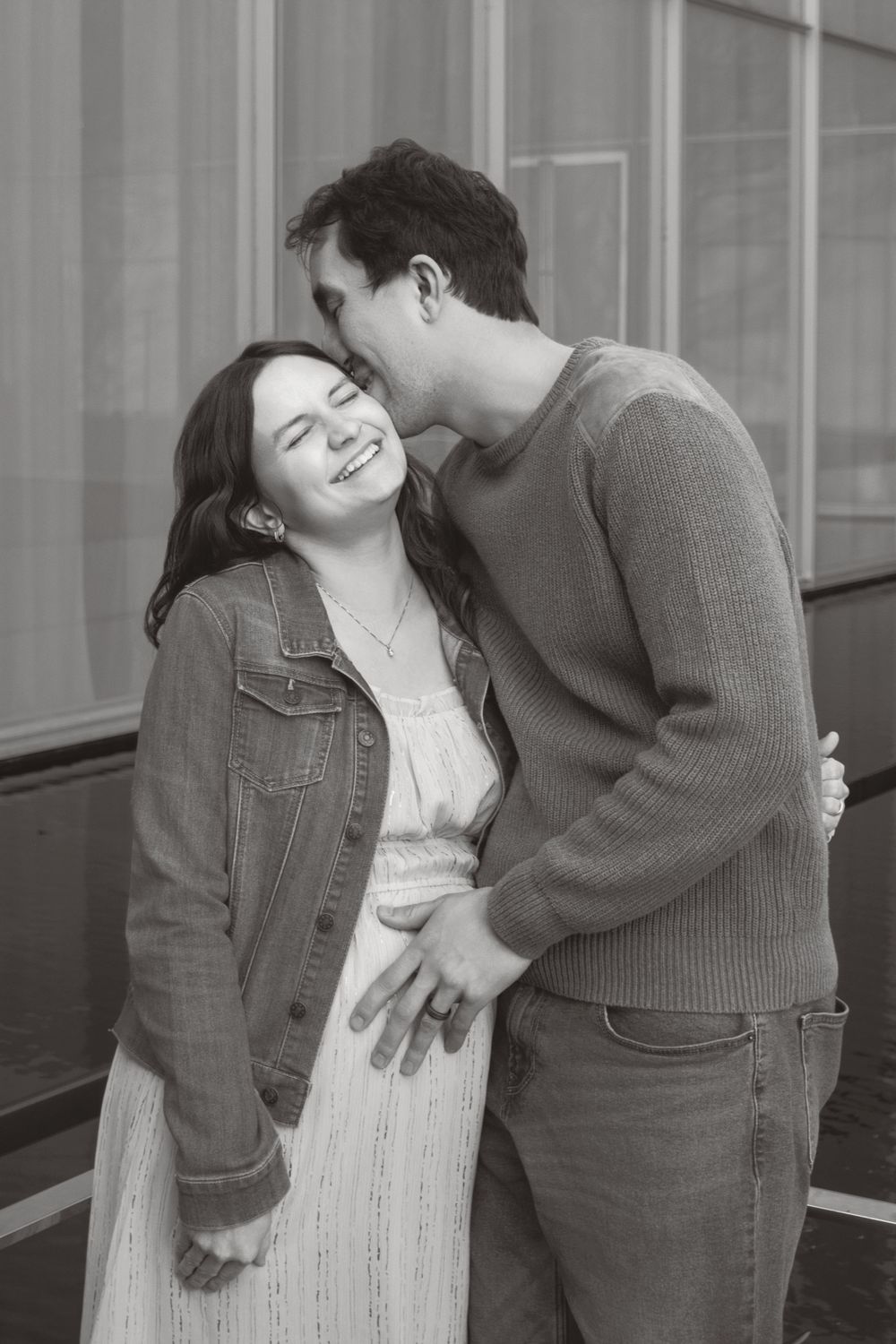 Black and white photo of a romantic couple sharing a tender moment together, wearing casual attire.