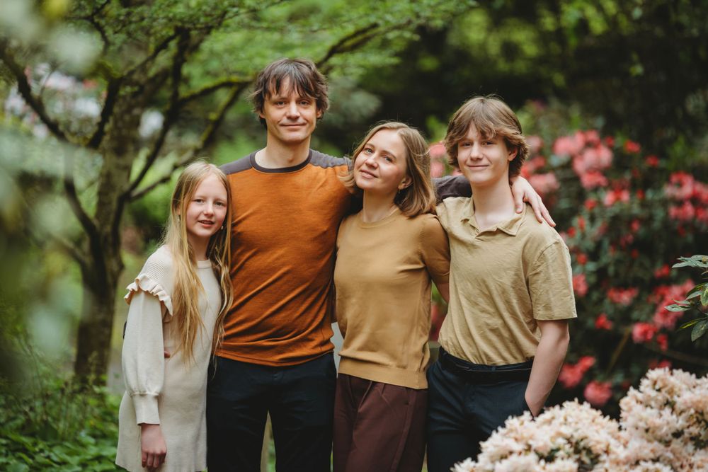 A group of four young people in casual autumn attire posing together in Bellevue botanical  garden with blooming flowers.