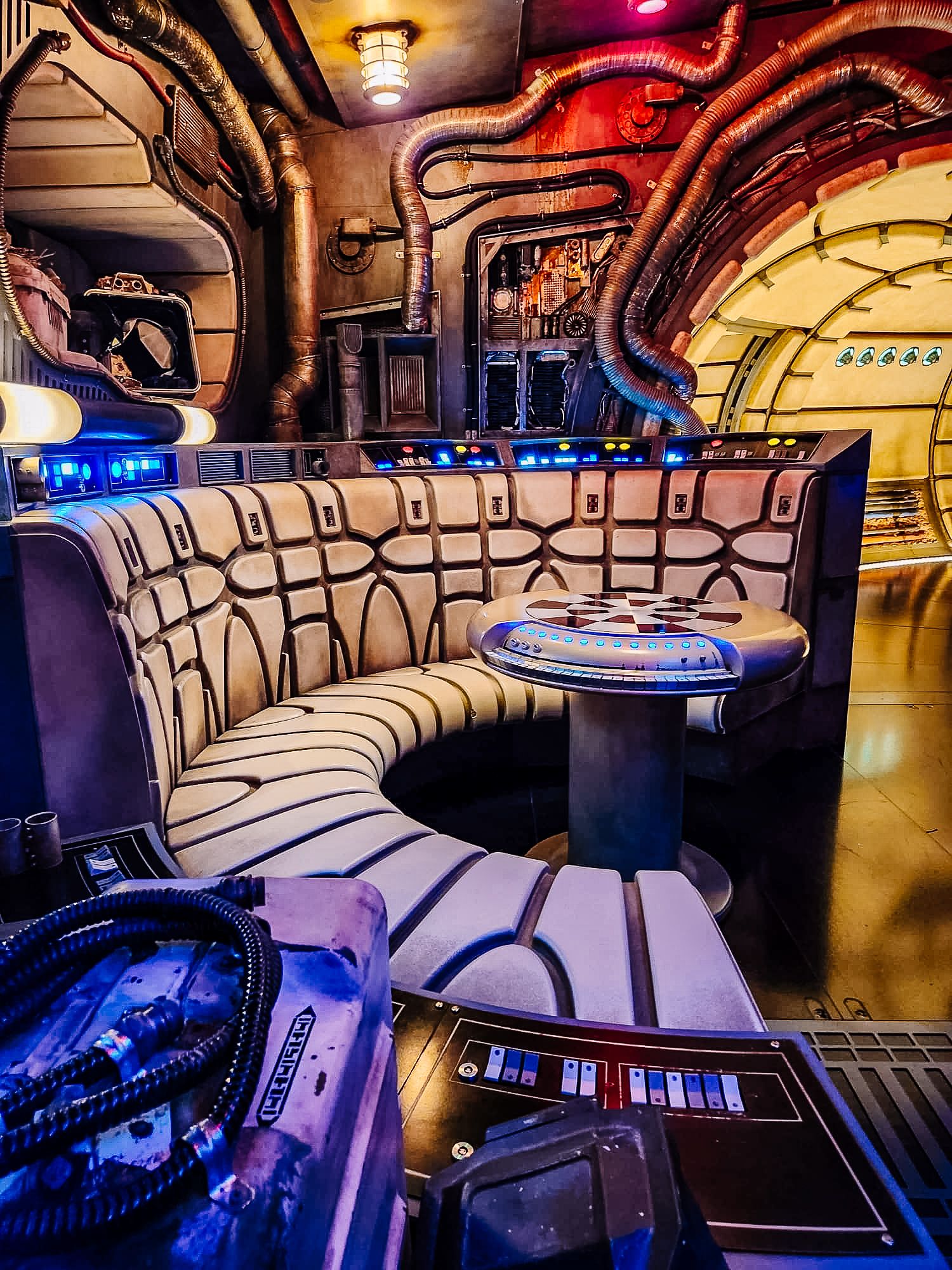 Luxurious curved booth seating and DJ equipment in a nightclub with dramatic red and gold lighting and Art Deco design elements.