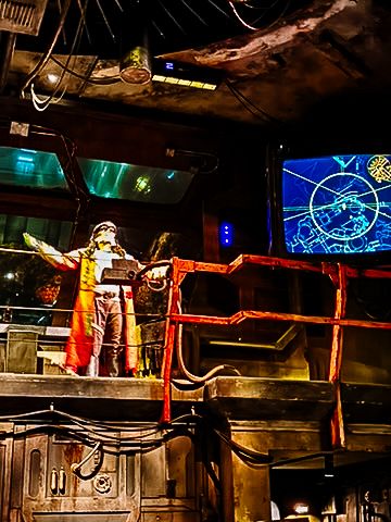 Theme park attraction with vintage space exploration aesthetic features glowing lights and mechanical elements in dark setting.